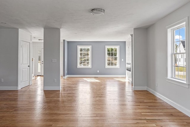 unfurnished living room featuring light wood-type flooring and baseboards