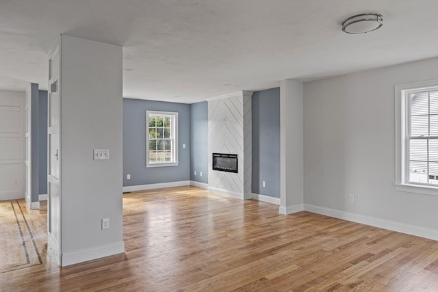 unfurnished living room featuring a fireplace, light wood finished floors, and baseboards