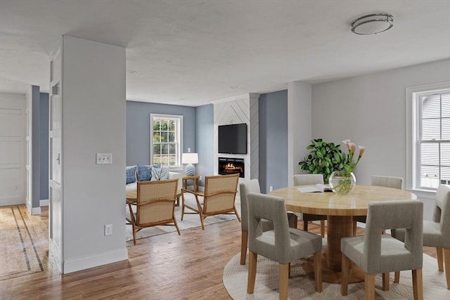 dining space with light wood-style flooring, baseboards, and a large fireplace