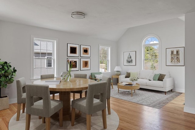 dining room featuring lofted ceiling, baseboards, and light wood-style flooring