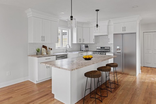 kitchen featuring a breakfast bar, light wood finished floors, stainless steel appliances, and white cabinets