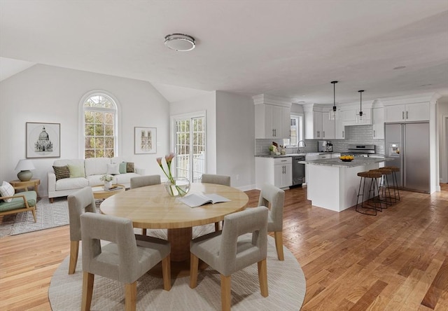 dining space featuring vaulted ceiling and light wood-type flooring