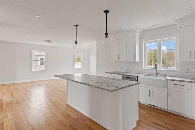 kitchen with light wood-style floors, plenty of natural light, a center island, and decorative backsplash