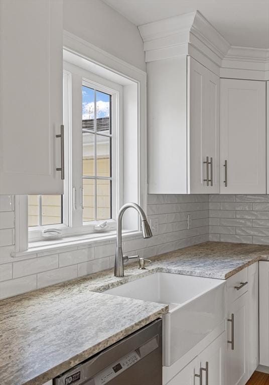 kitchen featuring white cabinets, backsplash, dishwashing machine, and a sink