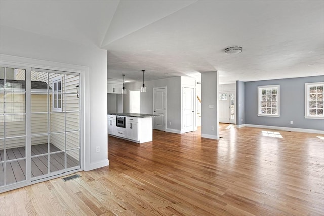 unfurnished living room with baseboards, visible vents, and light wood-style floors