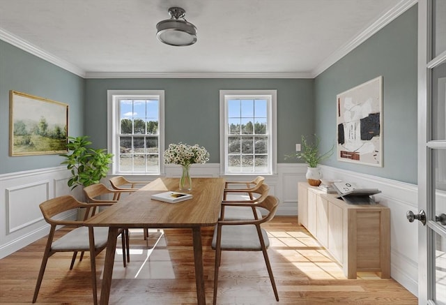 dining space with light wood-type flooring, a wealth of natural light, and ornamental molding