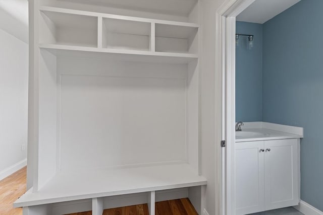 mudroom featuring wood finished floors, baseboards, and a sink