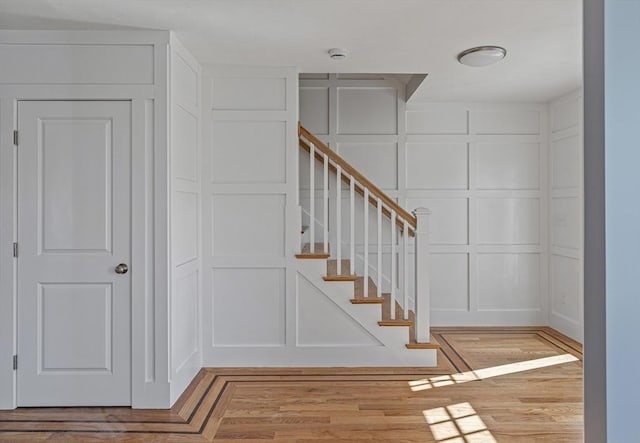 stairway with a decorative wall and wood finished floors