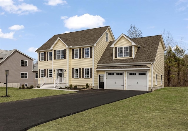 colonial inspired home featuring a front lawn, driveway, and roof with shingles