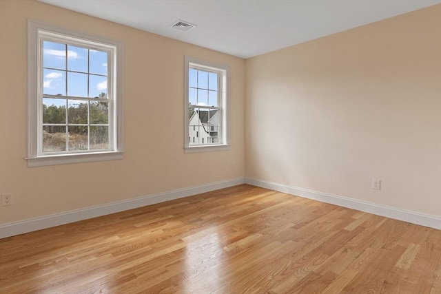 unfurnished room with baseboards, light wood finished floors, and visible vents