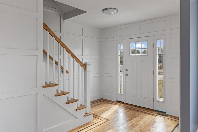 entrance foyer featuring light wood finished floors, stairs, and a decorative wall