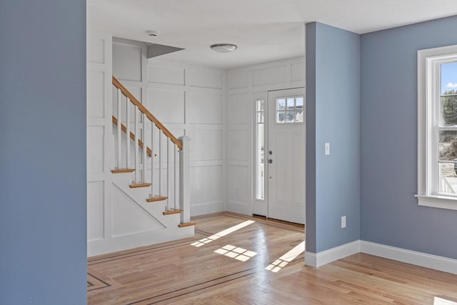 foyer featuring light wood finished floors, baseboards, and stairs