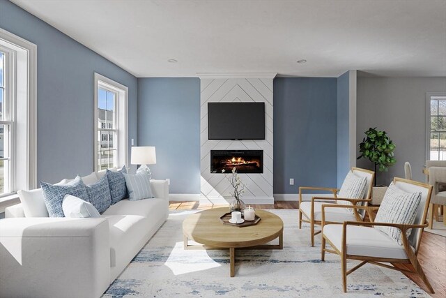 living area with a fireplace, wood finished floors, and baseboards