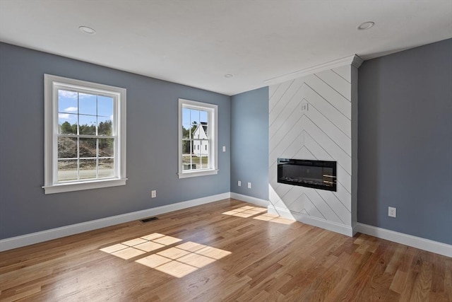unfurnished living room with a wealth of natural light, visible vents, and baseboards