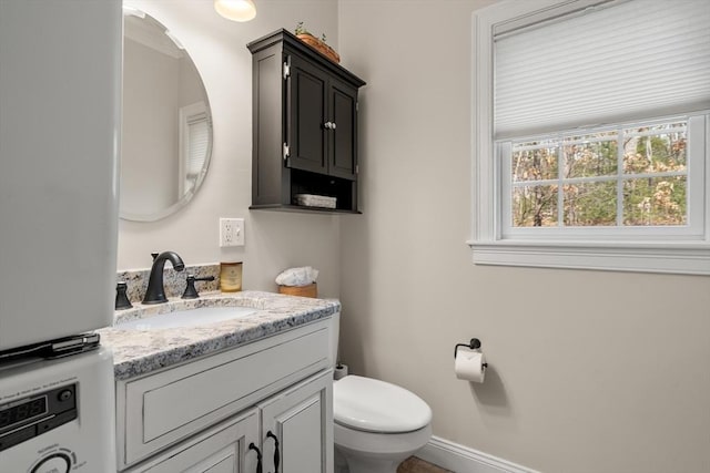 half bath with toilet, vanity, and baseboards