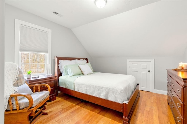 bedroom with visible vents, baseboards, light wood-type flooring, and lofted ceiling