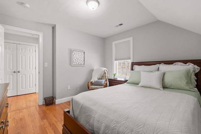 bedroom with visible vents, light wood-style flooring, baseboards, and vaulted ceiling