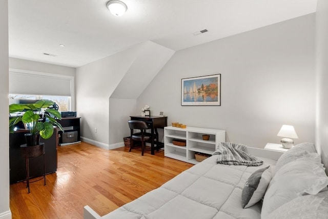 bedroom with light wood finished floors, visible vents, baseboards, and vaulted ceiling