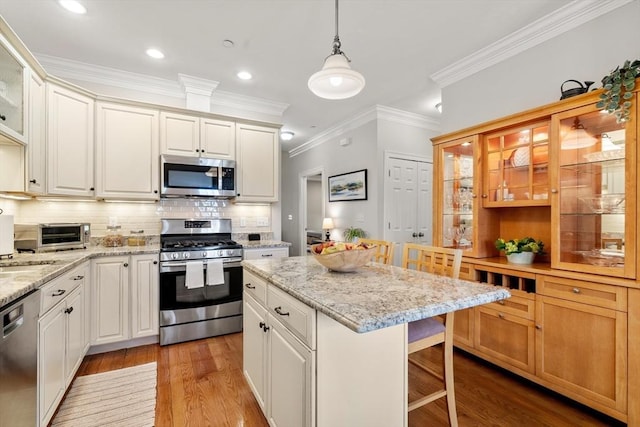 kitchen with a kitchen island, a breakfast bar, decorative backsplash, appliances with stainless steel finishes, and light wood-type flooring