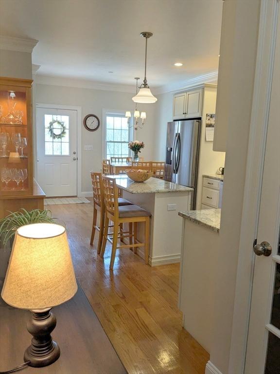 kitchen with light wood-style flooring, ornamental molding, a center island, stainless steel fridge, and a breakfast bar area