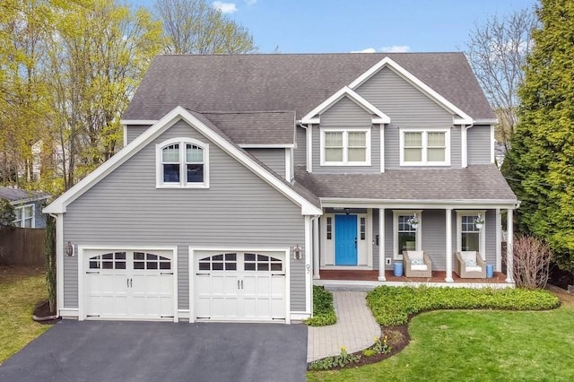 view of front of house with a porch, a garage, aphalt driveway, and a front yard