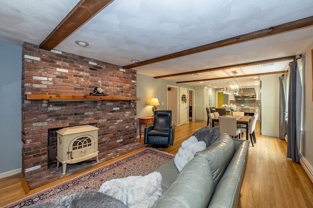 759 Main St, Boxford, MA 01921 - living room featuring beamed ceiling, light wood-style floors, a chandelier, and a wood stove