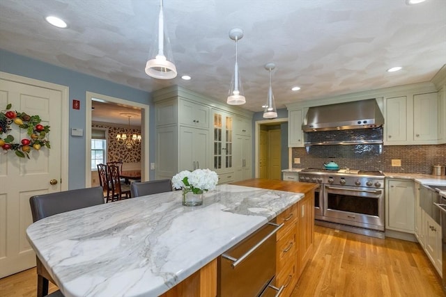 759 Main St, Boxford, MA 01921 - kitchen featuring wall chimney range hood, double oven range, light stone counters, light wood-style floors, and decorative backsplash