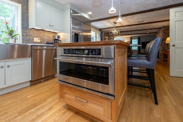 759 Main St, Boxford, MA 01921 - kitchen featuring stainless steel appliances, light wood-type flooring, healthy amount of natural light, white cabinetry, and beam ceiling