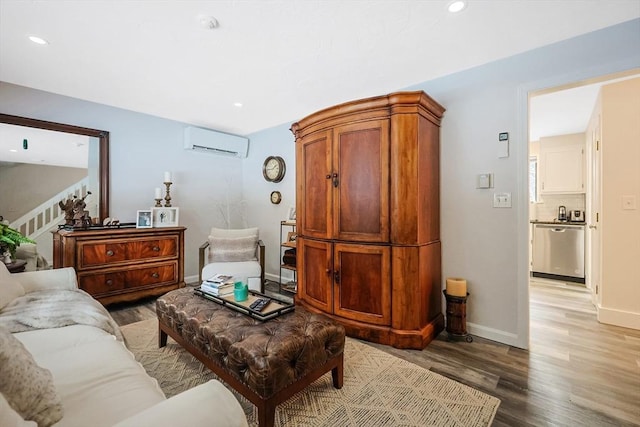 living room with an AC wall unit and light hardwood / wood-style floors