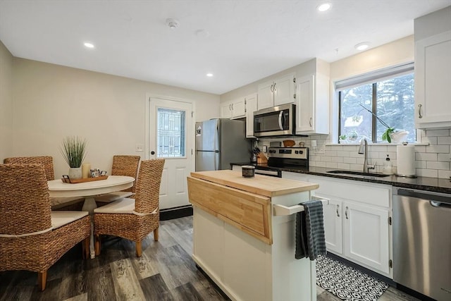 kitchen with appliances with stainless steel finishes, decorative backsplash, white cabinets, sink, and dark hardwood / wood-style flooring