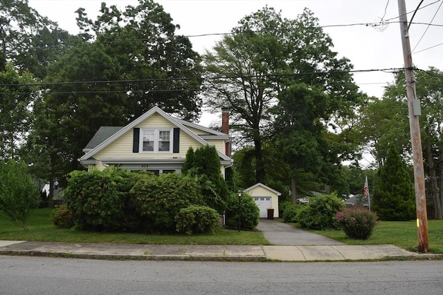 959 Ray St, Fall River, MA 02720 - view of front of house with an outdoor structure, a detached garage, driveway, and a chimney