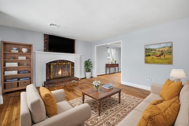 living room featuring a brick fireplace and hardwood / wood-style flooring