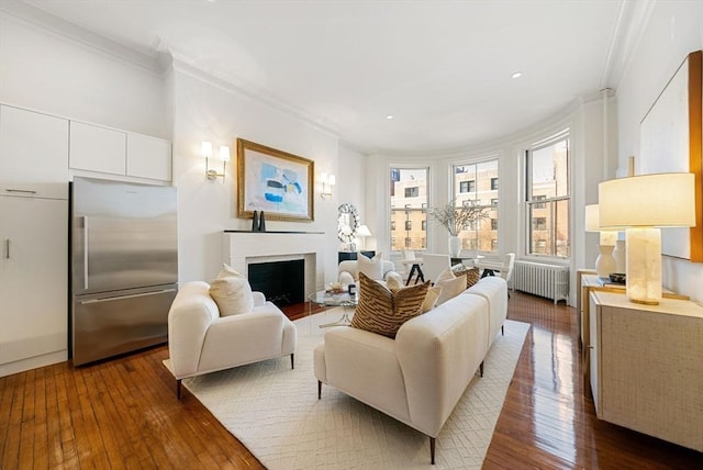 living room featuring dark hardwood / wood-style floors, radiator heating unit, ornamental molding, and a brick fireplace