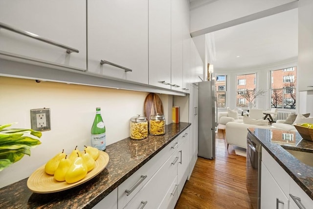 kitchen featuring dark hardwood / wood-style floors, dark stone countertops, white cabinetry, and appliances with stainless steel finishes