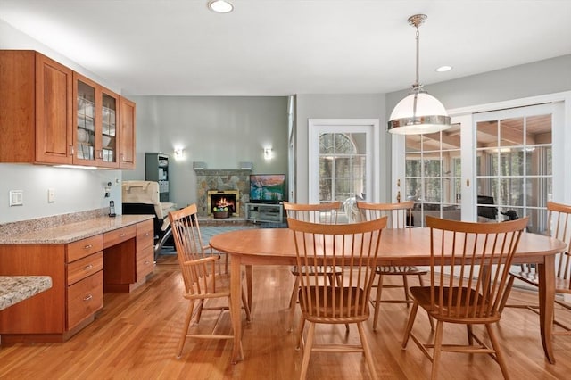 dining room with recessed lighting, a stone fireplace, and light wood-style floors