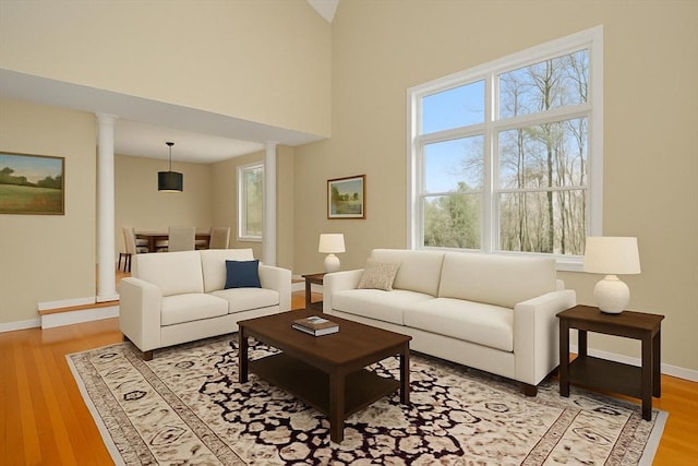 living area featuring baseboards, decorative columns, and light wood-type flooring