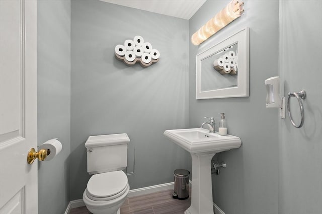 bathroom with toilet, baseboards, a sink, and wood finished floors