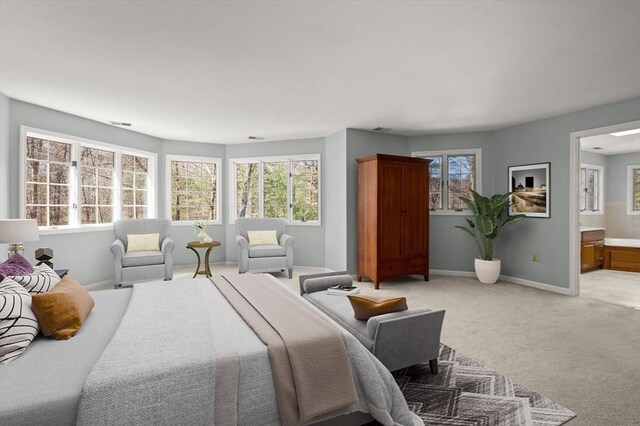 bedroom featuring baseboards, ensuite bath, and light colored carpet