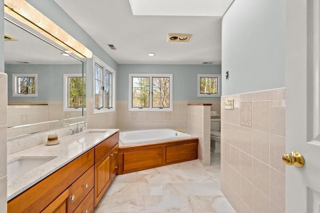 bathroom featuring a sink, tile walls, a bath, and visible vents