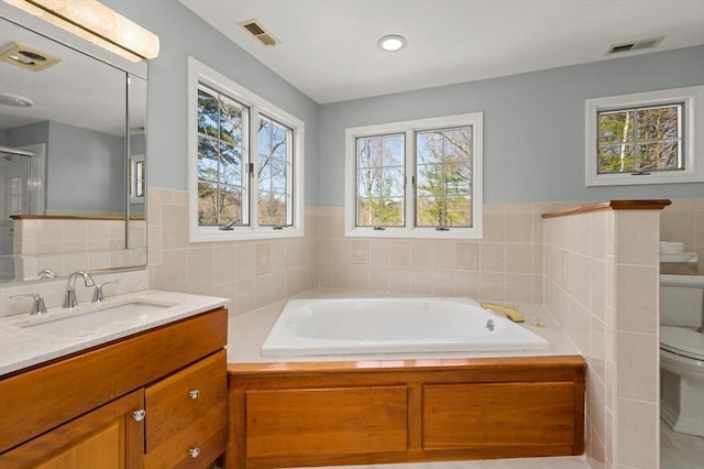 full bath with tile walls, vanity, toilet, and visible vents