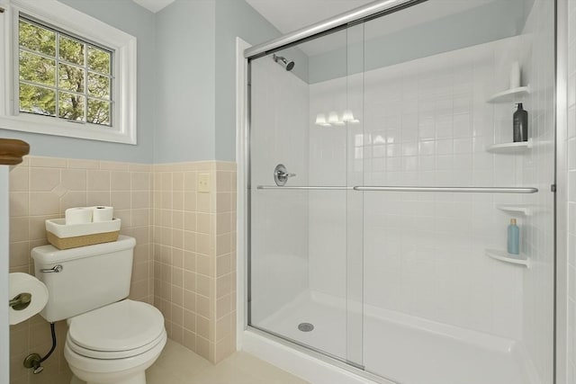 full bath with tile walls, tile patterned flooring, a stall shower, a wainscoted wall, and toilet