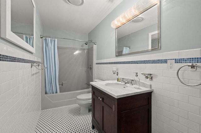 bathroom with vanity, tile walls, wainscoting, and shower / bathtub combination with curtain