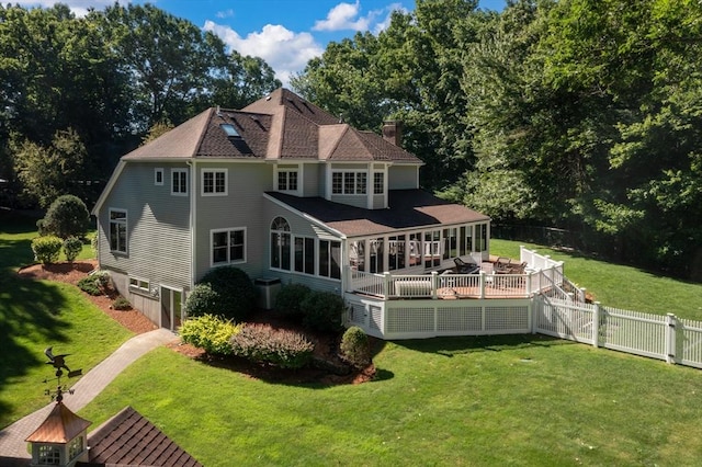 rear view of property with a lawn, a deck, a fenced backyard, a chimney, and an attached garage
