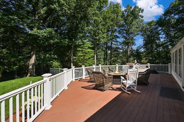 wooden deck featuring a lawn, an outdoor fire pit, and fence