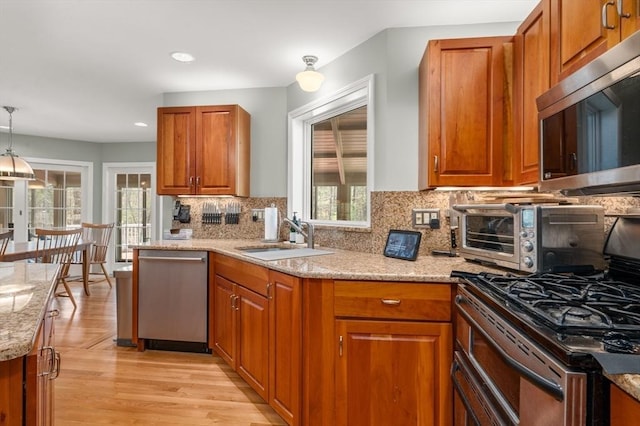 kitchen featuring a sink, light stone counters, plenty of natural light, and stainless steel appliances