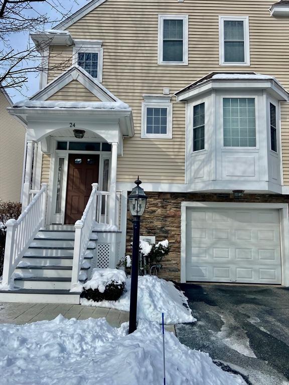 snow covered property entrance featuring a garage