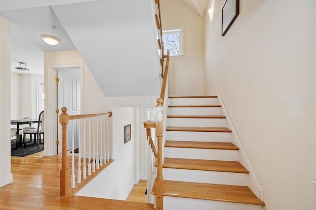 stairs featuring wood-type flooring and vaulted ceiling