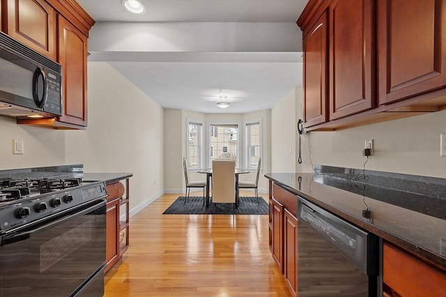 kitchen featuring dark stone counters, light hardwood / wood-style flooring, and black appliances