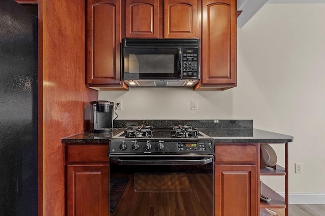 kitchen featuring dark stone countertops, light hardwood / wood-style floors, and black appliances