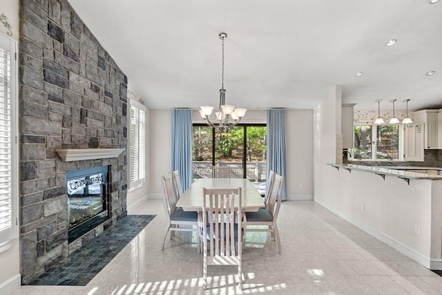 dining area featuring a chandelier, baseboards, a stone fireplace, and recessed lighting